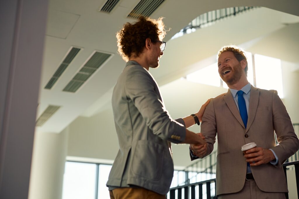Happy businessmen handshaking in a hallway of an office building.